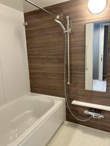a bathroom with a white tub and a mirror at ASOBO OSAKA Kuromon 2nd in Osaka