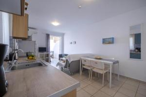 a kitchen with a sink and a table with chairs at Ferienwohnung Zesa Mit Balkon Und Meerblick in Kivérion