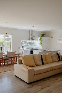 ダンズボローにあるPapillon Dunsborough Family & Pet Friendly Holiday Homeのソファとキッチンのあるリビングルーム