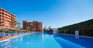 a large swimming pool with chairs and a building at Aparthotel Myramar Fuengirola in Fuengirola