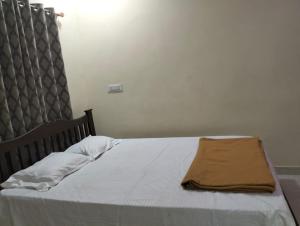 a bed with white sheets and a brown blanket on it at Suyog Homestay Malvan in Malvan