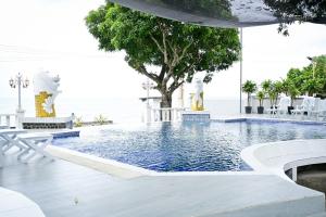 a swimming pool with white chairs and a tree at Crown of the Orient Beach Resort in Gloria