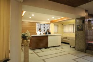 two people sitting at a reception desk in a hotel lobby at Hotel Mangalore International in Mangalore