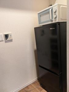 a microwave sitting on top of a black refrigerator at Colin Home Intimo Amigo in Tokyo