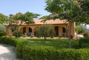 a yellow house with a green yard with trees at Il Girasole in Venturina Terme