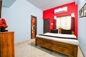 Un dormitorio con una cama con una pared roja. en Hotel O Spacious Villa, en Bhubaneshwar