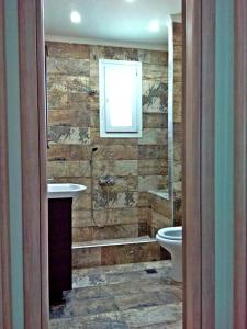 een badkamer met een douche, een wastafel en een toilet bij Iro Apartment in Néa Péramos