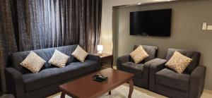 a living room with two chairs and a couch and a tv at المسواري سوس للوحدات السكنيه in Al Baha