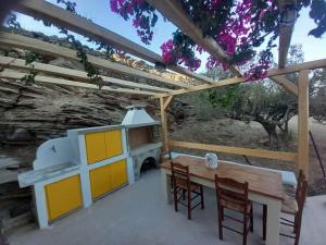 a patio with a table and chairs under a pergola at Kavourocheri beach house in Kithnos