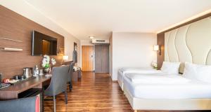 a hotel room with two beds and a desk at PLAZA Hotel Föhr am Bodensee in Friedrichshafen