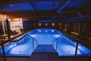 a large swimming pool with stairs in a building at Elixír Medical Wellness Hotel in Mórahalom