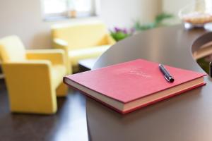 a red notebook sitting on a table with a pen on it at Hotel Mit-Mensch in Berlin