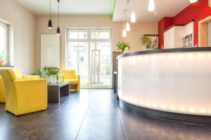 a waiting room with yellow chairs and a counter at Hotel Mit-Mensch in Berlin
