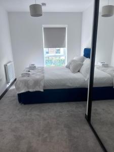a bedroom with a large bed and a mirror at The Ivy Abode 2 bedroom ApartmentParking in Harlow