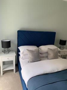 a bed with a blue headboard and two night stands at The Sunrise Den-Lovely 2 bedroom apartmentParking in Harlow