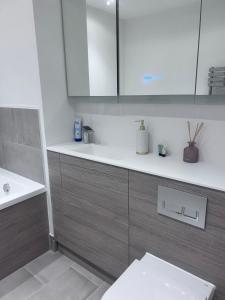 a bathroom with white and brown cabinets and a sink at The Sunrise Den-Lovely 2 bedroom apartmentParking in Harlow