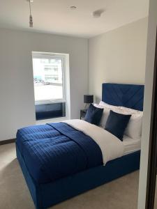 a bedroom with a blue and white bed with a window at The Sunrise Den-Lovely 2 bedroom apartmentParking in Harlow +14 photos