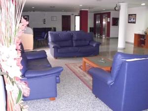 a living room with blue couches and a coffee table at Hotel Avenida de Canarias in Vecindario