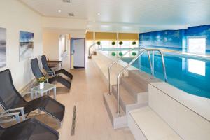 a swimming pool in a building with chairs and a swimming pool at Best Western Plus Arosa Hotel in Paderborn