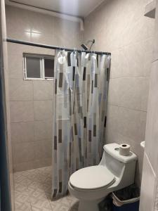 a bathroom with a toilet and a shower curtain at Cuartos Lupita descansa como en casa in Cabo San Lucas
