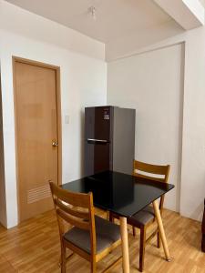 a black table with two chairs and a refrigerator at Sebastians Crib in Dasmariñas