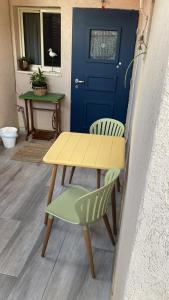 a yellow table and two chairs and a blue door at פינה קטנה ורומנטית in Shelomi