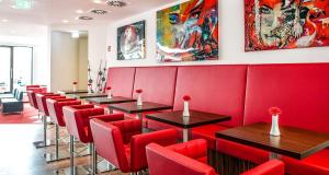 a row of tables and red chairs in a restaurant at PLAZA Premium Berlin Kurfürstendamm in Berlin