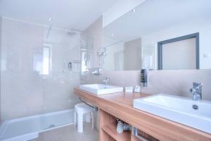 ein Badezimmer mit zwei Waschbecken und einer Badewanne und einem Spiegel in der Unterkunft Best Western Hotel Brunnenhof in Weibersbrunn