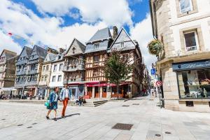 two people walking down a city street with buildings at La tente de kergomar in Ploumilliau +21 photos