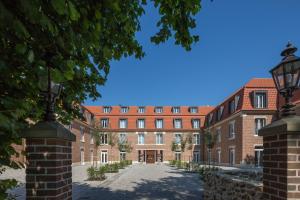 un grand bâtiment en briques rouges avec une allée. dans l'établissement Hofhotel Grothues-Potthoff, à Senden