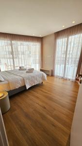 - une chambre avec un grand lit, du parquet et de grandes fenêtres dans l'établissement The Colors of Larnaca, à Larnaka