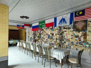 a dining room with tables and chairs and a wall with flags at Bohodir Guest House in Samarkand