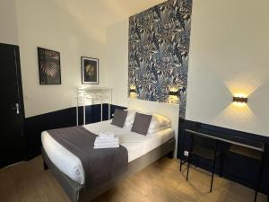 a bedroom with a bed and a table and a lamp at Hôtel Saint Eloi in Tours