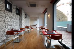 a restaurant with red tables and chairs and a brick wall at Exe Hotel El Magistral in Oviedo
