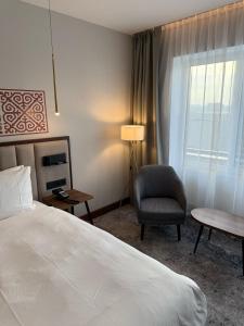 a bedroom with a bed and a chair and a window at Rahat Palace Hotel in Almaty