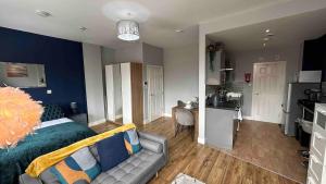 a bedroom with a bed and a couch and a kitchen at Spacious and homely city centre studio in Coventry