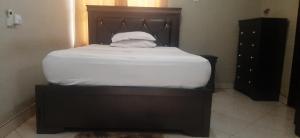 a bed with white sheets and a wooden head board at Adenab Jay Accommodation in Atasomanso