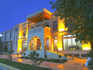 Un gran edificio con una fachada iluminada por la noche. en Caravan plaza Hotel, en Bukhara