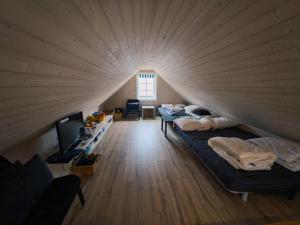 a room with two beds and a tv in a wooden ceiling at RO Turfroof Cottage with hot tub in cozy Skalavik in Skálavík