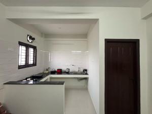 a small white kitchen with a sink and a door at TVK Grands 7 - Premium Two Bedroom Apartment in Coimbatore