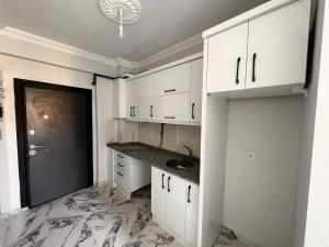 a kitchen with white cabinets and a marble floor at Güneş Rezidans in Nar