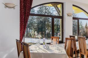 a dining room with a table and a large window at Hotel Casa Viorel jacuzzi & saunas in Poiana Brasov