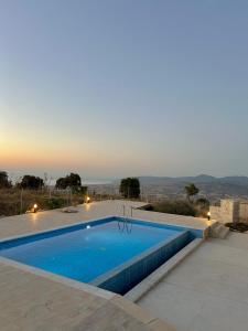 a swimming pool with a sunset in the background at Villa Terra Rosa in Kritou Terra