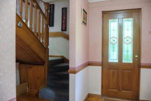 a hallway with a staircase and a wooden door at The Tolpuddle Cottage in Warburton