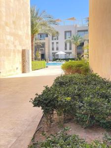 a courtyard with a building and some trees and bushes at Cozy 1BD in Mangroovy El Gouna in Hurghada