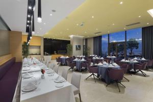 a restaurant with white tables and chairs and large windows at DoubleTree by Hilton Trabzon in Trabzon
