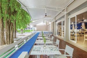 芭东海滩DoubleTree by Hilton Phuket Banthai Resort的餐厅里有一排桌子和椅子，周围有树