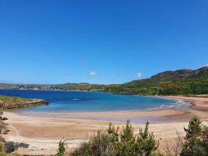 a beach with blue water and mountains in the background at Bains House, Gairloch in Gairloch
