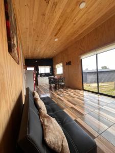 a living room with a black couch and wooden ceilings at Los Molinos Alto in Valdivia