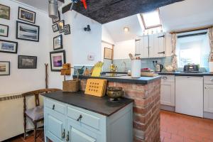 une cuisine avec des placards blancs et un comptoir en briques dans l'établissement Beach Cottage, à Haverfordwest 32 autres photos